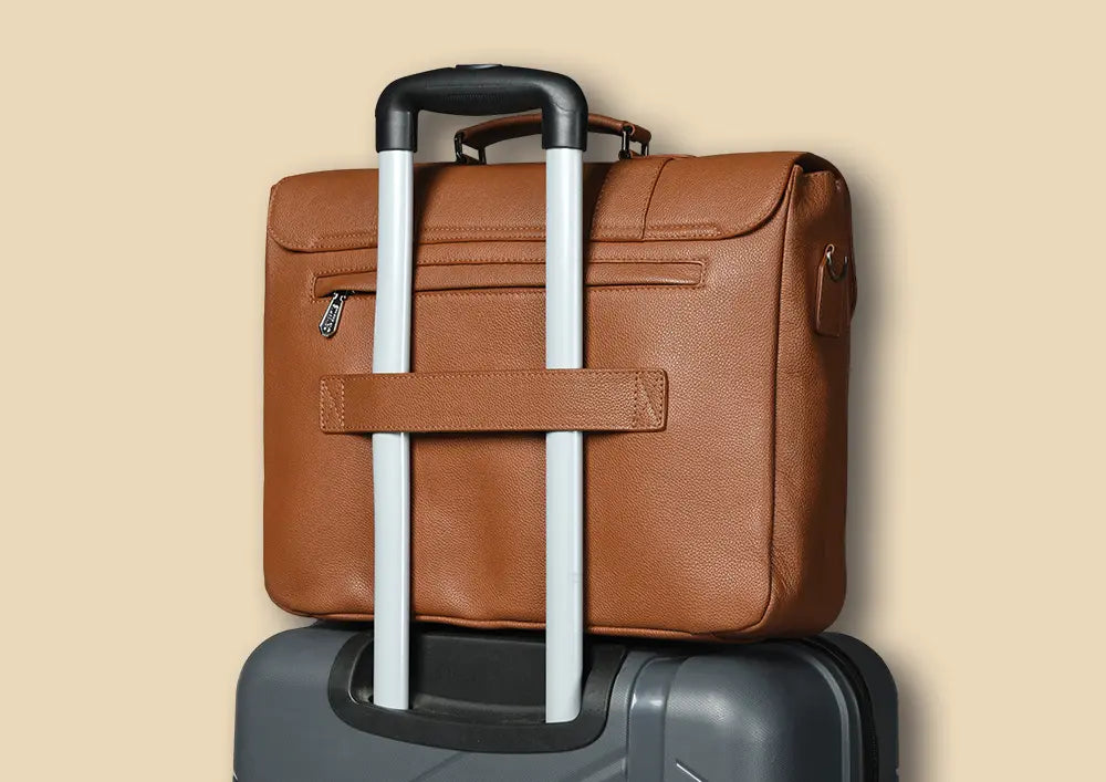 silvano code carrier messenger bag - tan leather messenger bag secured on top of a suitcase with trolley handle