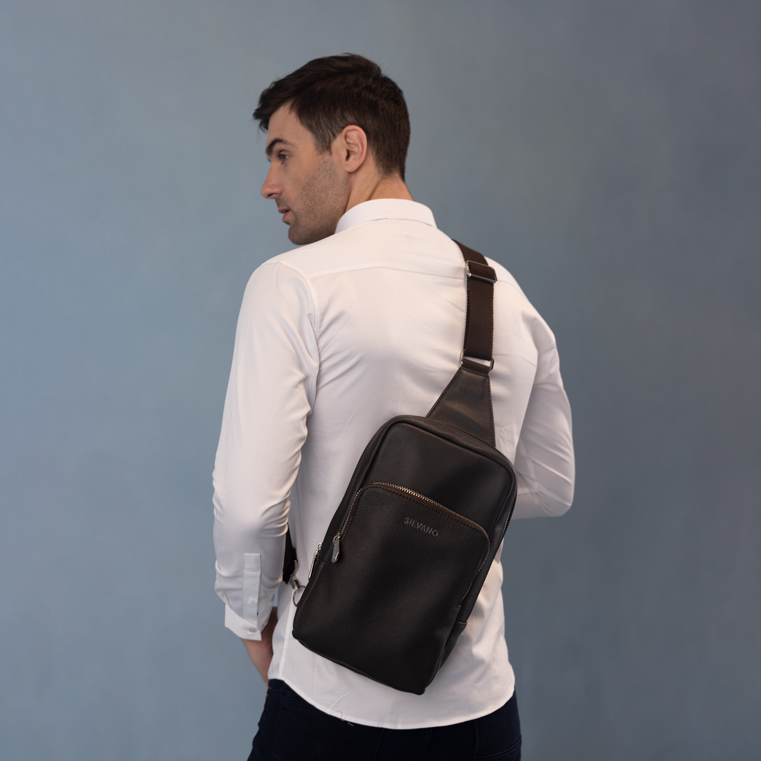 silvano jet bag crossbody bag - black leather crossbody worn by man in white shirt, shown from back view