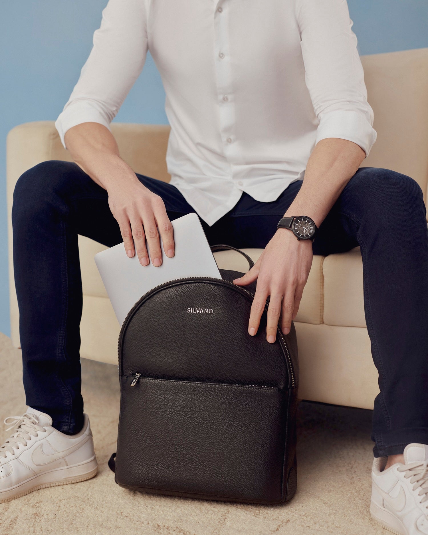 black leather backpack with front zip pocket and laptop compartment, styled by man in casual wear