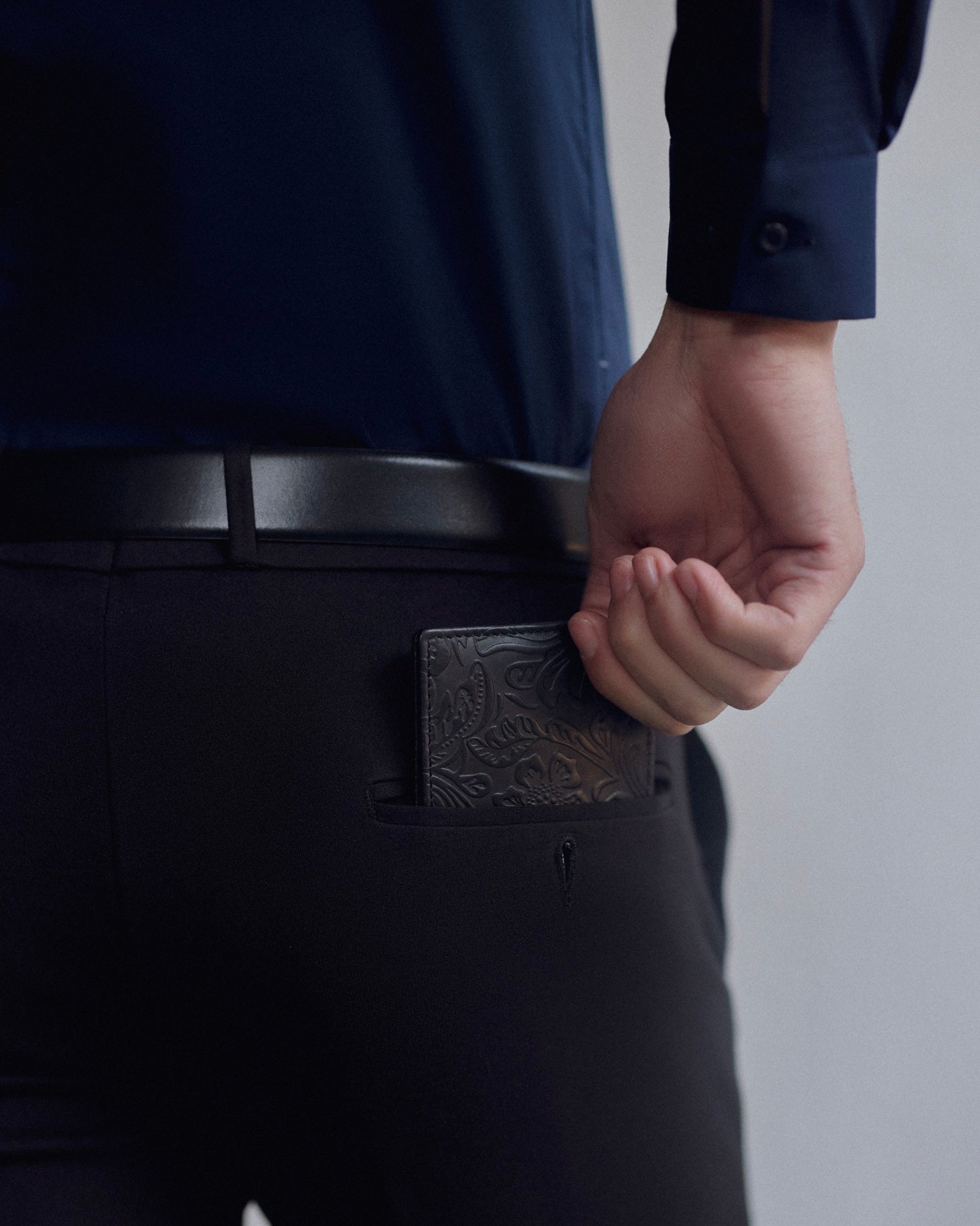 elite emboss wallet - black leather wallet with embossed design being placed into back pocket