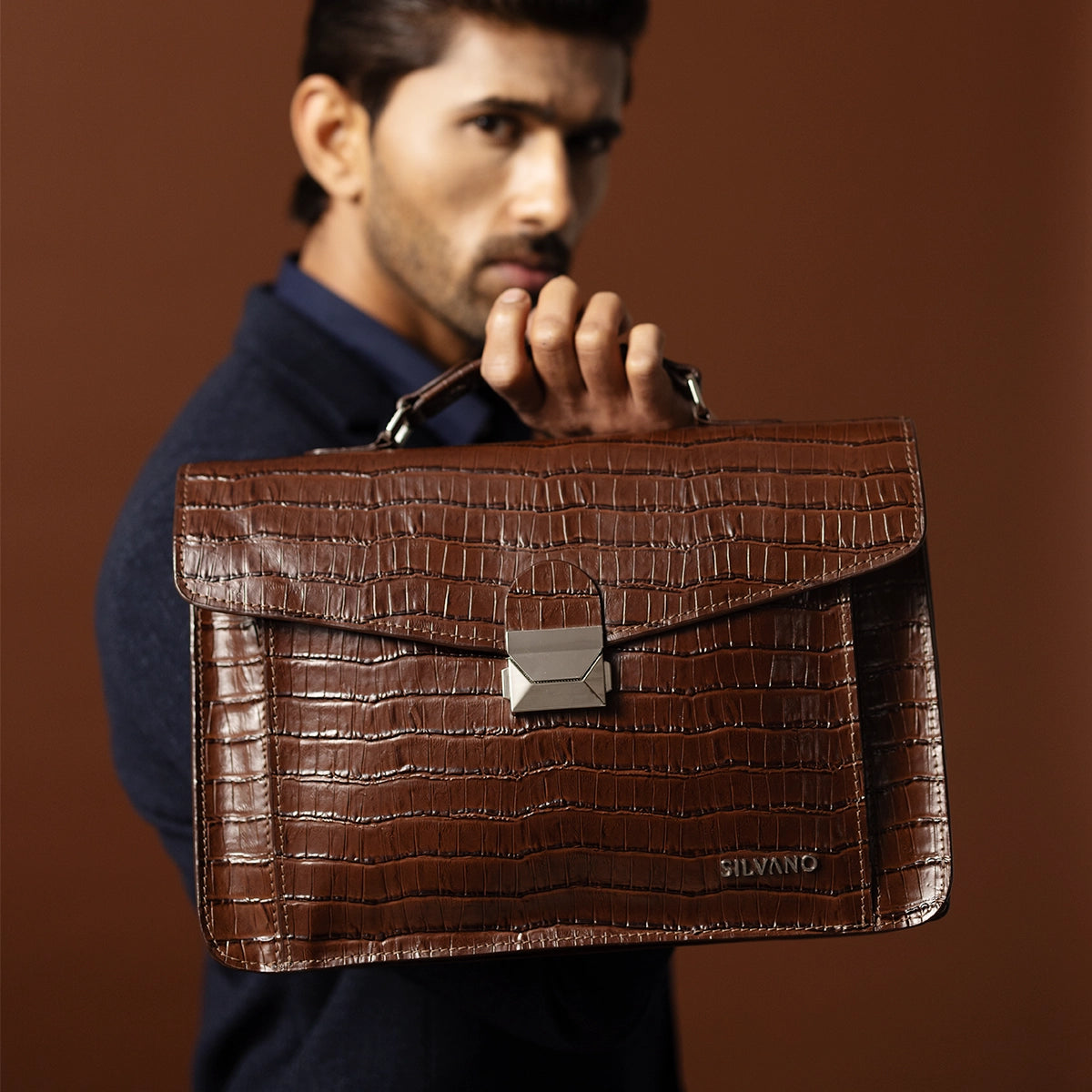 man holding silvano carrier caddy messenger bag - dark brown leather messenger bag