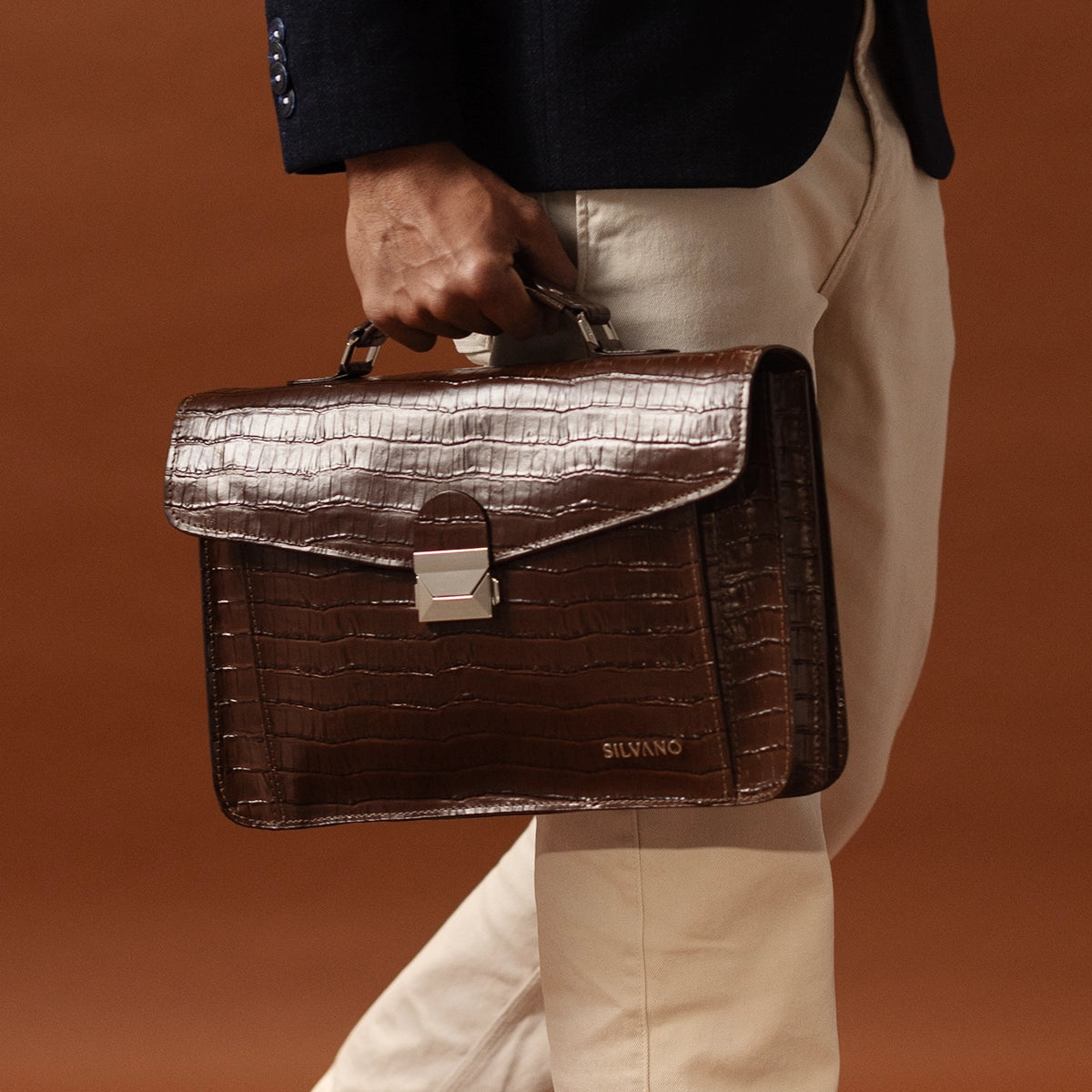 man holding silvano carrier caddy messenger bag - dark brown leather messenger bag