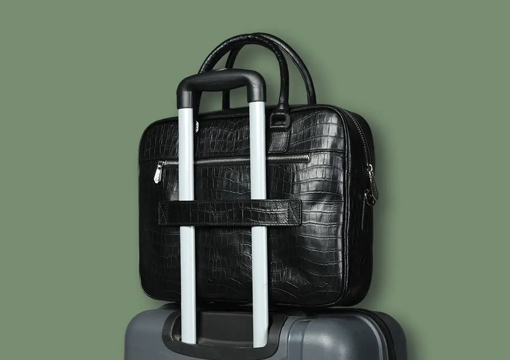 silvano byte bag laptop bag - black croco leather laptop bag secured on top of a suitcase with trolley handle